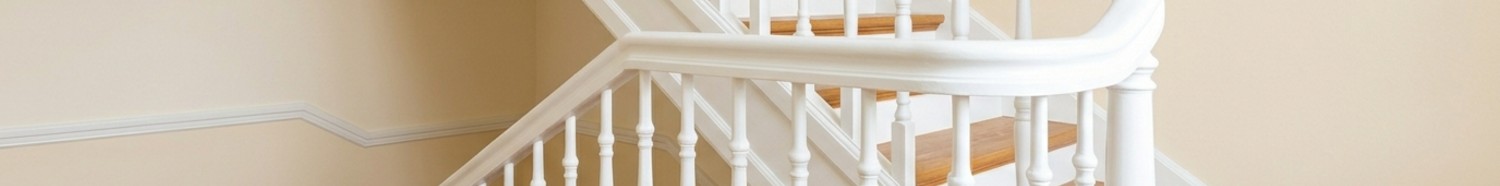 Frisch renoviertes und hell gestrichenes Treppenhaus mit Holzgeländer.